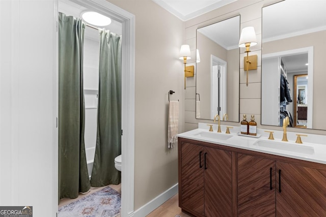 full bath featuring ornamental molding, a sink, toilet, and double vanity