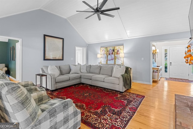 living area with baseboards, a ceiling fan, vaulted ceiling, and wood finished floors