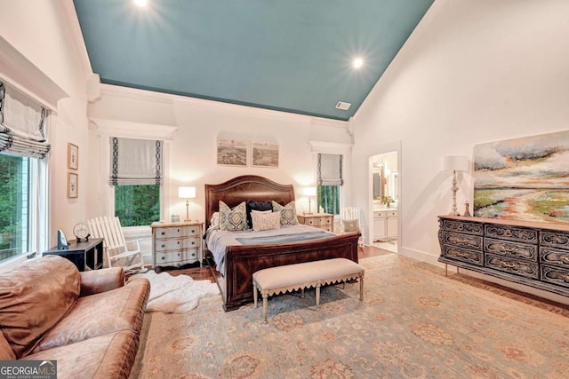 bedroom featuring ensuite bath and high vaulted ceiling