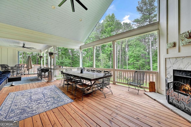 wooden deck with ceiling fan and a premium fireplace