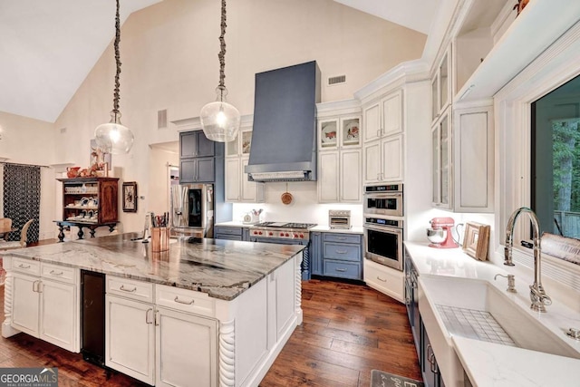 kitchen featuring appliances with stainless steel finishes, sink, wall chimney range hood, high vaulted ceiling, and hanging light fixtures