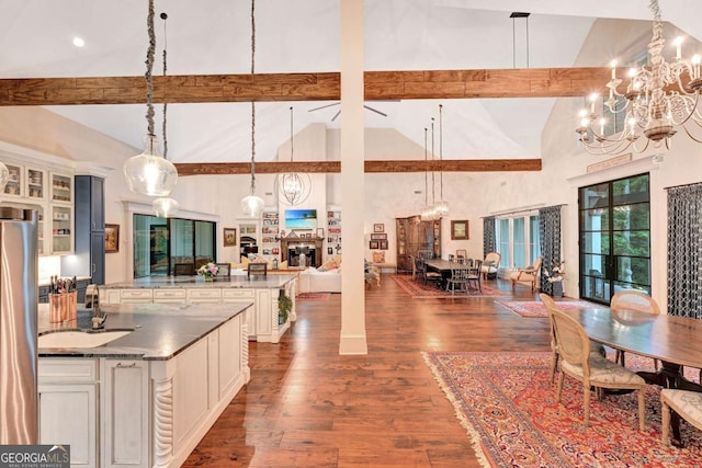 kitchen with beam ceiling, dark hardwood / wood-style flooring, high vaulted ceiling, and hanging light fixtures