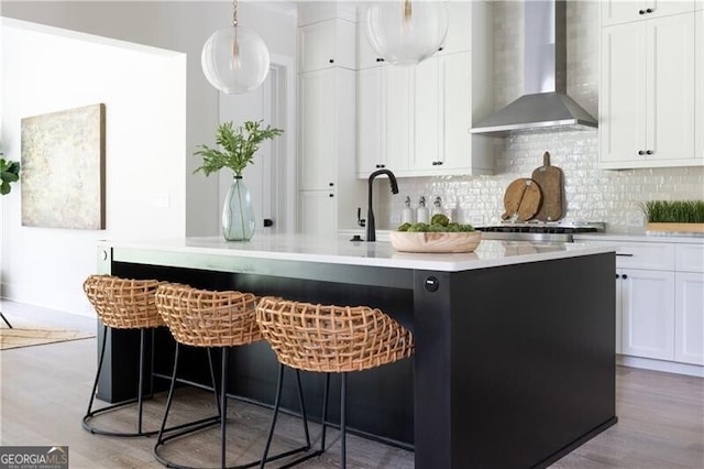 kitchen featuring tasteful backsplash, white cabinets, and wall chimney range hood