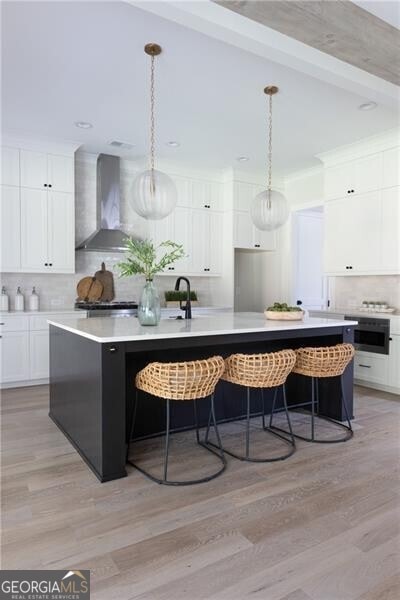 kitchen featuring tasteful backsplash, high end stainless steel range, white cabinets, and wall chimney range hood