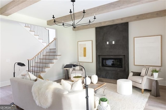 living room featuring a fireplace, beam ceiling, light hardwood / wood-style floors, and a chandelier