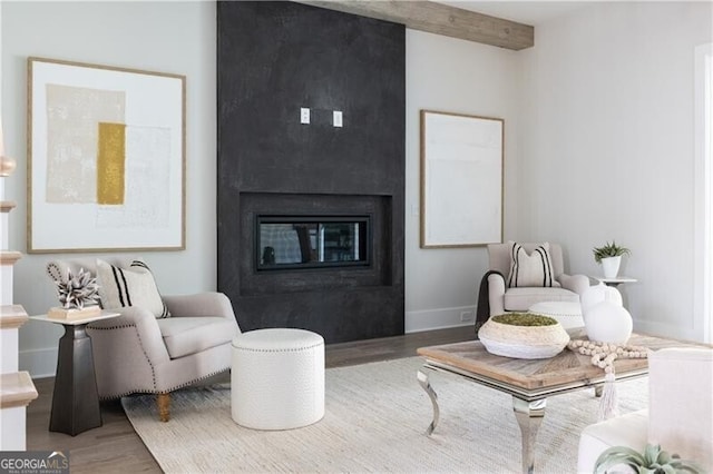 living room featuring beamed ceiling, wood-type flooring, and a fireplace