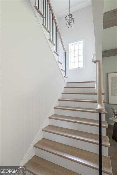 stairway with hardwood / wood-style flooring and an inviting chandelier