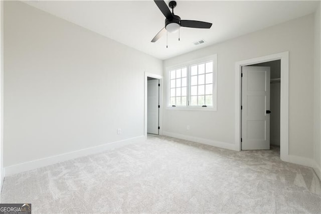 unfurnished bedroom featuring ceiling fan, light colored carpet, and a spacious closet