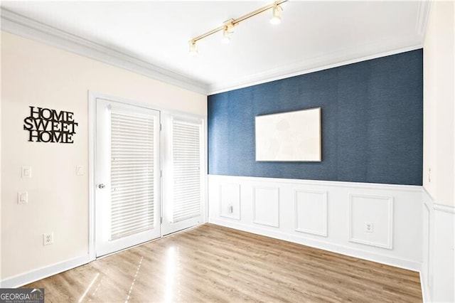 unfurnished room featuring hardwood / wood-style flooring, ornamental molding, and track lighting