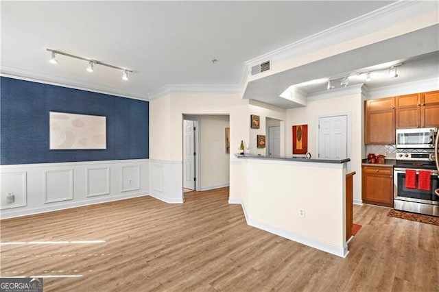 kitchen with backsplash, crown molding, light hardwood / wood-style flooring, and stainless steel appliances