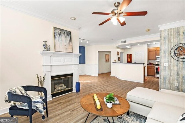 living room with light hardwood / wood-style floors, ceiling fan, and ornamental molding