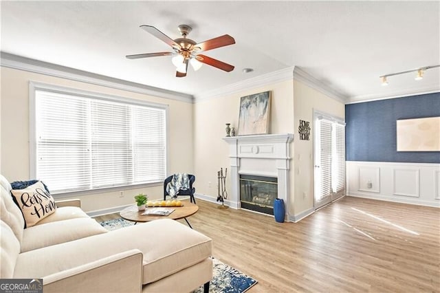 living room featuring ornamental molding, wood-type flooring, and ceiling fan