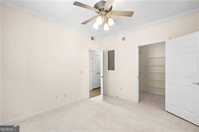 unfurnished bedroom with ornamental molding, a walk in closet, light colored carpet, electric panel, and a closet