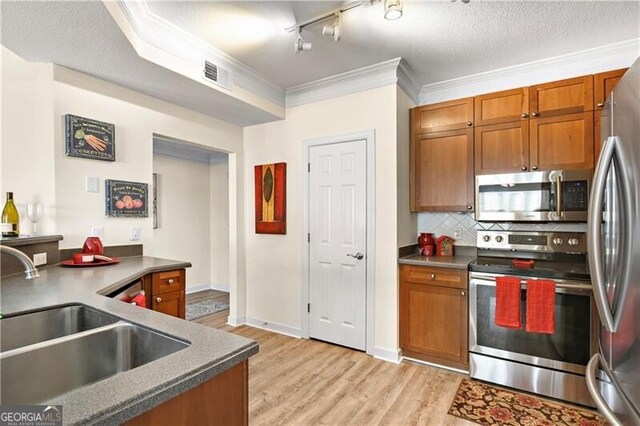 kitchen with backsplash, rail lighting, sink, a textured ceiling, and appliances with stainless steel finishes