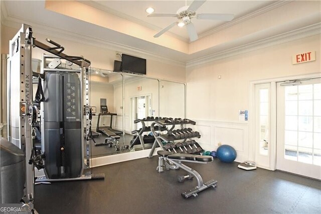 workout area featuring a raised ceiling, crown molding, and ceiling fan