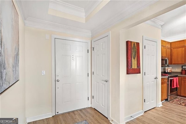 entrance foyer with light hardwood / wood-style flooring, ornamental molding, and a raised ceiling