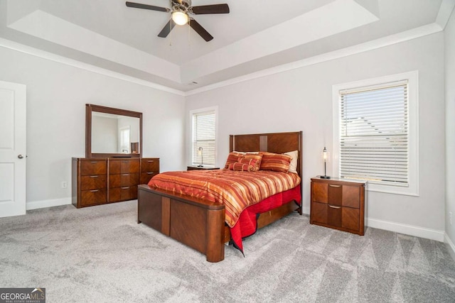 bedroom featuring multiple windows, a tray ceiling, ceiling fan, and light colored carpet