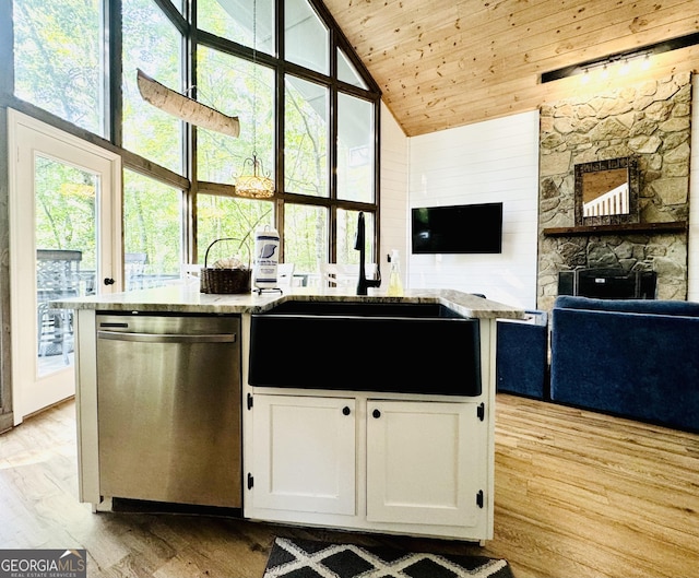 kitchen featuring high vaulted ceiling, white cabinetry, stainless steel dishwasher, and a wealth of natural light