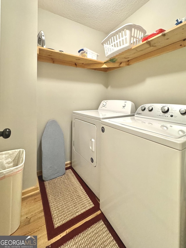 washroom with light hardwood / wood-style floors, independent washer and dryer, and a textured ceiling