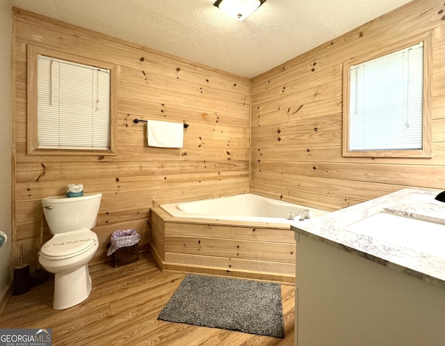 bathroom with hardwood / wood-style floors, vanity, a textured ceiling, and wooden walls