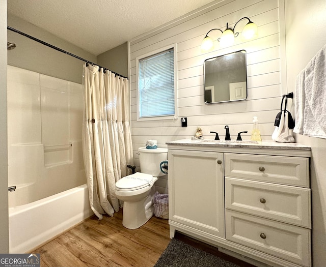 full bathroom with vanity, a textured ceiling, shower / bathtub combination with curtain, hardwood / wood-style floors, and wood walls