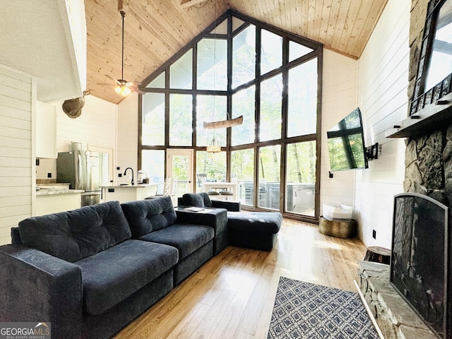 living room with a stone fireplace, wooden ceiling, high vaulted ceiling, and light hardwood / wood-style flooring