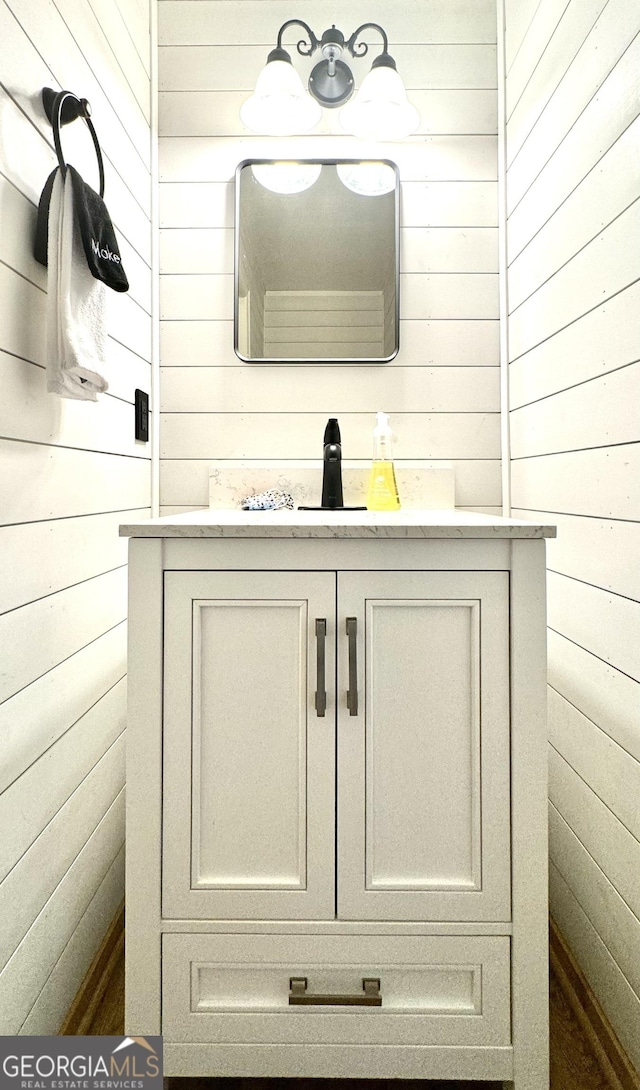 bathroom featuring vanity and wood walls