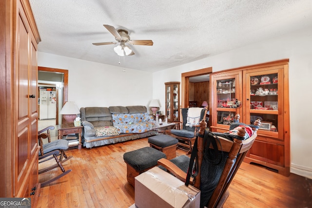 living room with ceiling fan, light hardwood / wood-style floors, and a textured ceiling