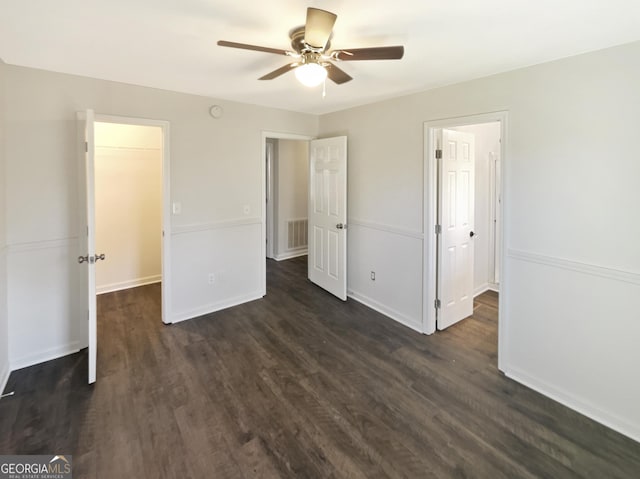 unfurnished bedroom featuring a walk in closet, ceiling fan, a closet, and dark hardwood / wood-style floors