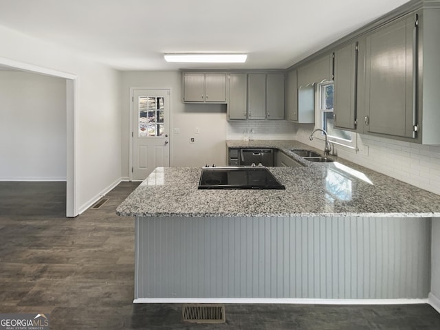 kitchen featuring sink, gray cabinets, tasteful backsplash, stone countertops, and kitchen peninsula