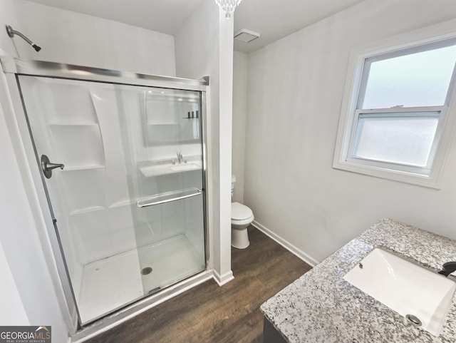 bathroom with hardwood / wood-style floors, vanity, toilet, and walk in shower