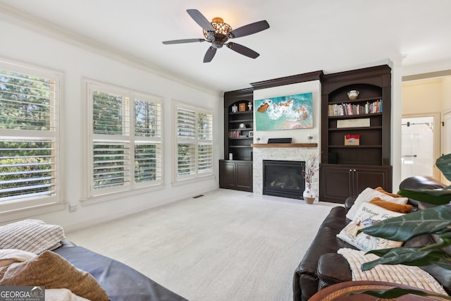 living room with a fireplace, light colored carpet, ceiling fan, and ornamental molding