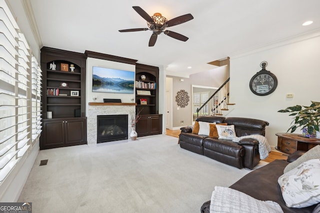 living room featuring light colored carpet, a stone fireplace, ceiling fan, and ornamental molding