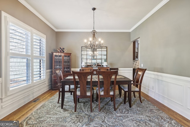 dining room featuring ornamental molding, hardwood / wood-style flooring, and a notable chandelier