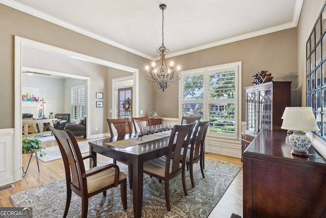 dining space featuring light hardwood / wood-style flooring, a chandelier, and ornamental molding