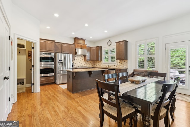 kitchen with a center island, backsplash, light hardwood / wood-style flooring, a kitchen bar, and stainless steel appliances