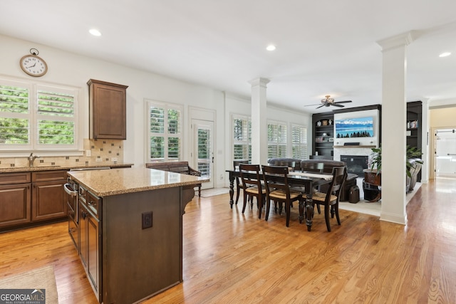 kitchen with tasteful backsplash, light stone counters, ceiling fan, light hardwood / wood-style floors, and a kitchen island