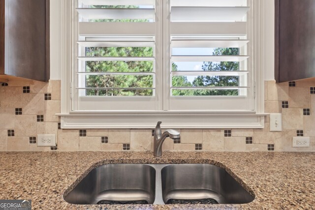 kitchen featuring light stone countertops, tasteful backsplash, and sink