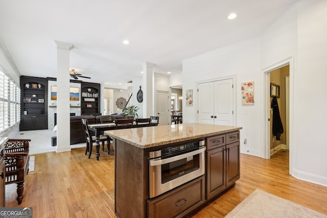 kitchen featuring a center island, oven, ceiling fan, light wood-type flooring, and dark brown cabinets