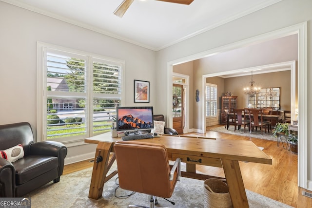 home office with light wood-type flooring, an inviting chandelier, and ornamental molding