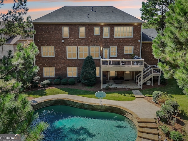 back house at dusk with a swimming pool side deck and a patio