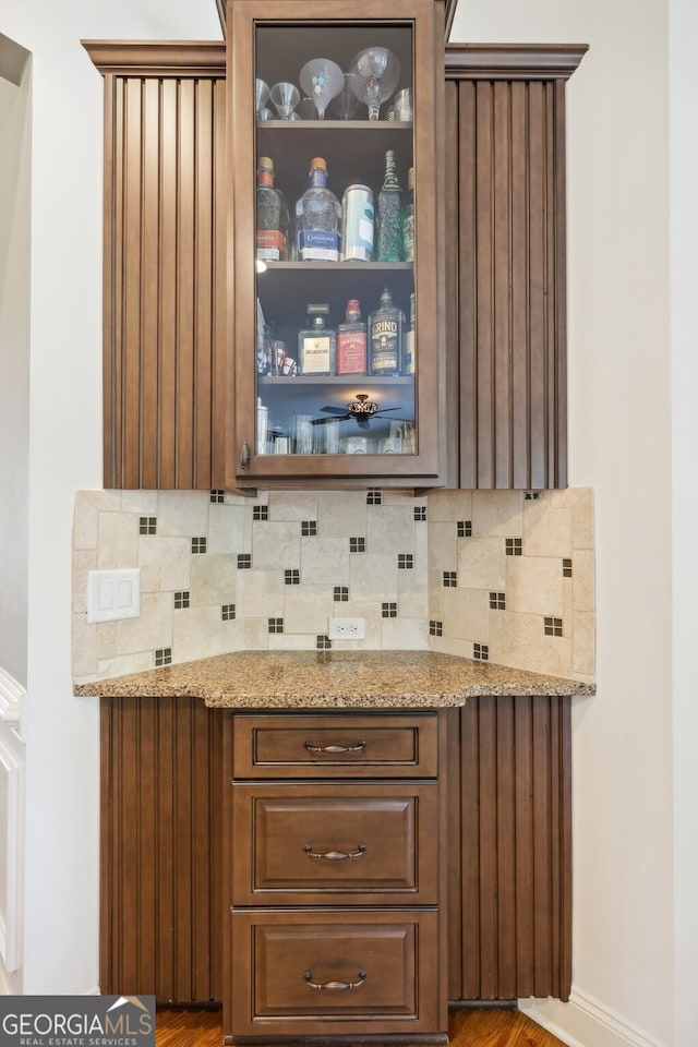 bar featuring light stone countertops and tasteful backsplash