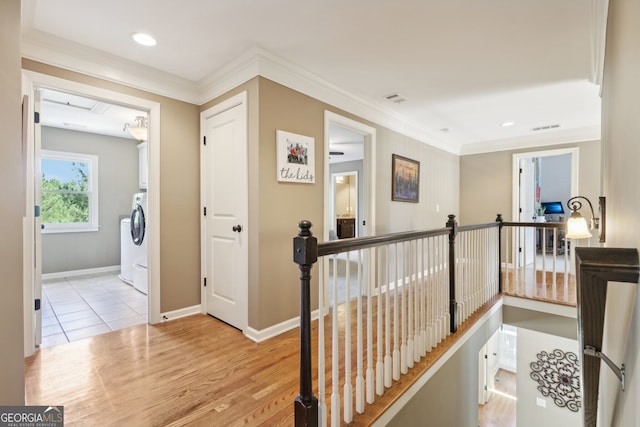 hallway with washer / dryer, light hardwood / wood-style floors, and ornamental molding