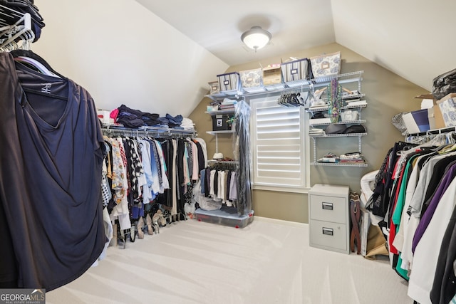 walk in closet with light colored carpet and vaulted ceiling