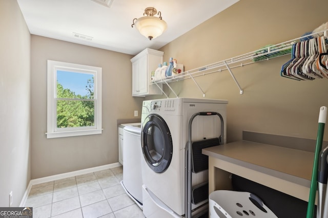 laundry room featuring washer and clothes dryer, cabinets, and light tile patterned floors