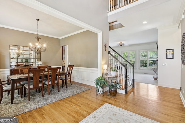 dining room featuring ceiling fan with notable chandelier, light hardwood / wood-style floors, and crown molding