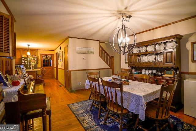 dining area featuring a notable chandelier, light hardwood / wood-style flooring, and ornamental molding