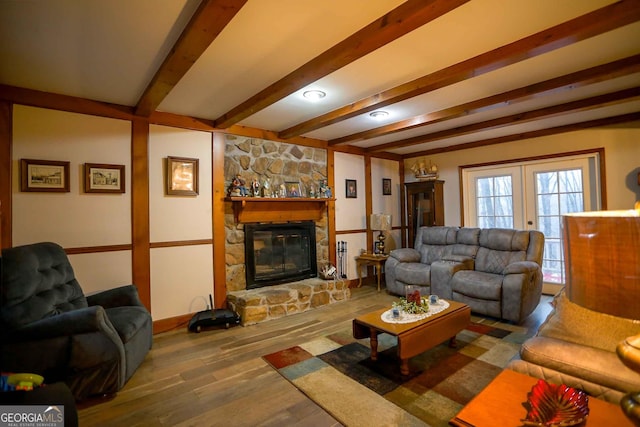 living room featuring hardwood / wood-style floors, french doors, beamed ceiling, and a stone fireplace