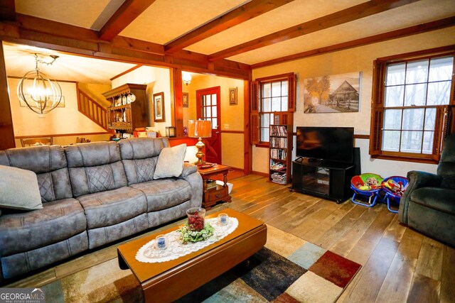 living room with beamed ceiling, hardwood / wood-style flooring, and an inviting chandelier