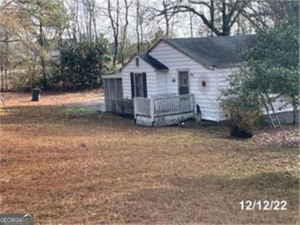 view of front of property with a sunroom, a front lawn, and a wooden deck